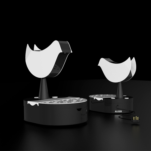 Two black glossy bases with white curved shells on top, set on a dark surface (Alessi design) for a modern decorative audio or sculpture piece.