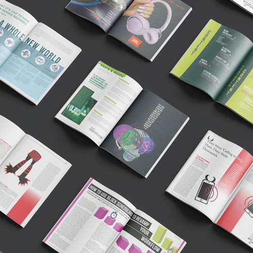 Aerial view of multiple open magazines scattered on a dark surface, showing colorful article spreads and illustrations.