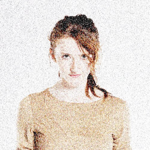 Portrait of a young woman with light brown hair in a beige sweater, looking at the camera.