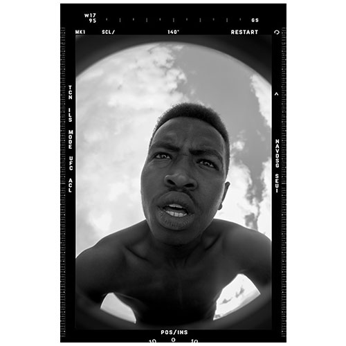 Close-up black-and-white self-portrait of a shirtless man, taken with a fisheye lens, Earth visible behind him.