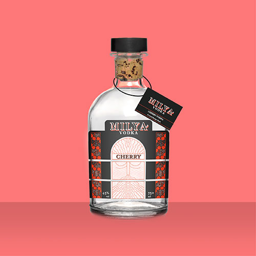 Bottle of Millya Cherry Vodka with a labeled front, cork stopper, and hanging tag on a pink background.